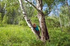 En medelålders kvinna lutade mot ett björkträd i skogen royaltyfria foton En medelålders kvinna lutade mot ett björkträd i skogen royaltyfria foton