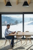 En mogen man som sitter p? tabellen i nytt hem, genom att anv?nda minnestavlan arkivbild En mogen man som sitter p? tabellen i nytt hem, genom att anv?nda minnestavlan arkivbild
