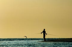 En silhouetted man fiskar på solnedgången längs den barfota stranden, Florida arkivfoton En silhouetted man fiskar på solnedgången längs den barfota stranden, Florida arkivfoton