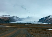 En smal väg i en öken med härliga kullar och berg i bakgrunden royaltyfri foto En smal väg i en öken med härliga kullar och berg i bakgrunden royaltyfri foto
