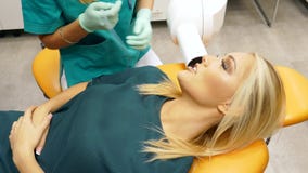 En tandläkare tar en röntgenstråle av kvinnligpatientÂs tänder stock video En tandläkare tar en röntgenstråle av kvinnligpatientÂs tänder stock video