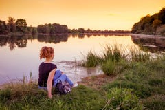 En ung flicka på flodbanken beundrar naturen under sunset_en royaltyfria bilder En ung flicka på flodbanken beundrar naturen under sunset_en royaltyfria bilder