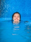 En ung le flickasimning i pölen med blått bevattnar fri Kvinnligt huvud ovanför vattnet i swimpool royaltyfri fotografi En ung le flickasimning i pölen med blått bevattnar fri Kvinnligt huvud ovanför vattnet i swimpool royaltyfri fotografi