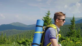 En ung man med en ryggsäck stiger stigande Stående av en sund och lycklig turist i bergen lager videofilmer En ung man med en ryggsäck stiger stigande Stående av en sund och lycklig turist i bergen lager videofilmer