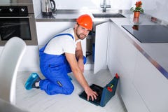 En ung repairman reparerar ett kökskåp med hjälpmedel arkivfoton En ung repairman reparerar ett kökskåp med hjälpmedel arkivfoton