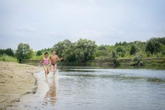 En verano, los niños corren a lo largo de la orilla del río imagen de archivo libre de regalías En verano, los niños corren a lo largo de la orilla del río imagen de archivo libre de regalías