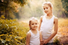 Enfance, famille, amitié et concept de personnes - deux soeurs heureuses d'enfants étreignant dehors photographie stock Enfance, famille, amitié et concept de personnes - deux soeurs heureuses d'enfants étreignant dehors photographie stock