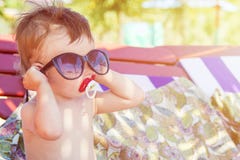 Enfant mignon dans des lunettes de soleil se reposant sur une chaise longue sur la plage tropicale de sable photos stock Enfant mignon dans des lunettes de soleil se reposant sur une chaise longue sur la plage tropicale de sable photos stock