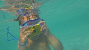 Enfant se baignant dans l'océan et prenant des photos avec l'appareil-photo imperméable banque de vidéos Enfant se baignant dans l'océan et prenant des photos avec l'appareil-photo imperméable banque de vidéos
