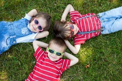 Enfants de sourire gais heureux, s'étendant sur une herbe, port chanté photo stock Enfants de sourire gais heureux, s'étendant sur une herbe, port chanté photo stock