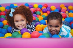 Enfants de sourire mignons dans la piscine de boule d'éponge photos stock Enfants de sourire mignons dans la piscine de boule d'éponge photos stock