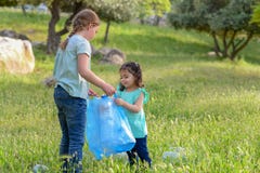 Enfants nettoyant en parc Enfants volontaires avec un sac de d?chets nettoyant des ordures, mettant la bouteille en plastique en image stock Enfants nettoyant en parc Enfants volontaires avec un sac de d?chets nettoyant des ordures, mettant la bouteille en plastique en image stock