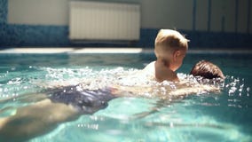 Enfileiramento do homem novo sob a água com seu filho louro na parte traseira O rapaz pequeno está acima da água Dentro piscina video estoque Enfileiramento do homem novo sob a água com seu filho louro na parte traseira O rapaz pequeno está acima da água Dentro piscina video estoque