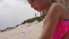 Enfrente a menina feliz que joga e que faz o bolo de areia e forme-a na praia do verão video estoque Enfrente a menina feliz que joga e que faz o bolo de areia e forme-a na praia do verão video estoque