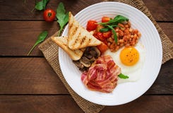 Engelsk frukost - stekt ägg, bönor, tomater, champinjoner, bacon och rostat bröd royaltyfri bild Engelsk frukost - stekt ägg, bönor, tomater, champinjoner, bacon och rostat bröd royaltyfri bild