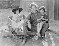 Engendrez se reposer avec ses deux filles sur un petit chariot sur une ferme (toutes les personnes représentées ne sont pas plus Photo stock Engendrez se reposer avec ses deux filles sur un petit chariot sur une ferme (toutes les personnes représentées ne sont pas plus Photo stock