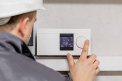 Engineer adjusting thermostat for efficient automated heating system Engineer adjusting thermostat for efficient automated heating system