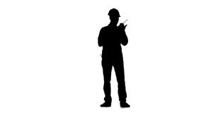 Engineer in a helmet works as a drill. Silhouette. White background. Slow motion stock footage Engineer in a helmet works as a drill. Silhouette. White background. Slow motion stock footage