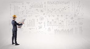 Engineer holding a plan and standing with graphs, charts and reports on the background royalty free stock photo Engineer holding a plan and standing with graphs, charts and reports on the background royalty free stock photo