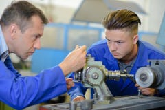 Engineer setting up equipment being watched by apprentice stock photography Engineer setting up equipment being watched by apprentice stock photography