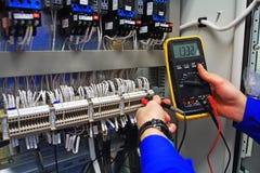 Engineer tests industrial electrical circuits with a multimeter in the control terminal box
