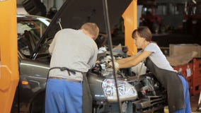 Engineers working with car engine. Female and male workers repairing car engine Engineers working with car engine. Female and male workers repairing car engine