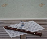 English teacup and saucer with floral decor and silver rim and a block flute on a sheet of music stock photography English teacup and saucer with floral decor and silver rim and a block flute on a sheet of music stock photography