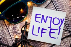 Enjoy life motivational handwritten message on a paper with blue color on wooden background with lights spread in unmistakable hea royalty free stock photos Enjoy life motivational handwritten message on a paper with blue color on wooden background with lights spread in unmistakable hea royalty free stock photos