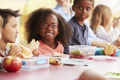 Enseñe a los niños que comen almuerzos llenos juntos en una tabla foto de archivo Enseñe a los niños que comen almuerzos llenos juntos en una tabla foto de archivo