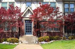 Entrance of brick Tudor Revival home with Chinese Maple trees on both sides of the door and crumbling cement porch royalty free stock image Entrance of brick Tudor Revival home with Chinese Maple trees on both sides of the door and crumbling cement porch royalty free stock image