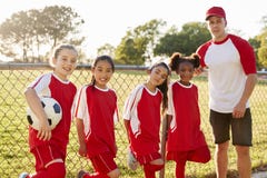 Entrenador y chicas jóvenes en un equipo de fútbol que mira a la cámara foto de archivo Entrenador y chicas jóvenes en un equipo de fútbol que mira a la cámara foto de archivo