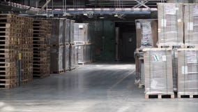 Entrepôt avec des supports et des étagères, remplis de boîtes en carton, enveloppées dans l'aluminium sur les palettes en bois cl images stock Entrepôt avec des supports et des étagères, remplis de boîtes en carton, enveloppées dans l'aluminium sur les palettes en bois cl images stock