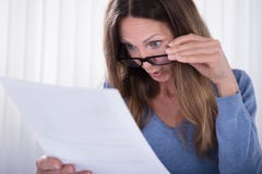 Entsetzte Frau, die Dokument im Büro betrachtet lizenzfreies stockbild Entsetzte Frau, die Dokument im Büro betrachtet lizenzfreies stockbild
