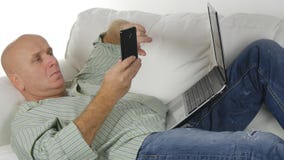 Entspannter Mann, der im Couch-Text unter Verwendung Smartphones stillsteht lizenzfreie stockbilder Entspannter Mann, der im Couch-Text unter Verwendung Smartphones stillsteht lizenzfreie stockbilder