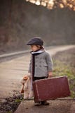 Entzückender Junge auf einem Bahnhof, auf den Zug mit Koffer und Teddybären wartend lizenzfreie stockfotografie Entzückender Junge auf einem Bahnhof, auf den Zug mit Koffer und Teddybären wartend lizenzfreie stockfotografie