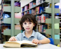 Entzückendes kleines Kind, Junge, sitzend in einer Bibliothek, Lesebücher lizenzfreies stockbild Entzückendes kleines Kind, Junge, sitzend in einer Bibliothek, Lesebücher lizenzfreies stockbild