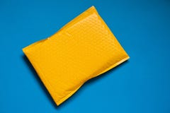 Enveloppe jaune faite en enveloppe de bulle pour empêcher quelque chose de se cogner ou antichoc sur le fond bleu photographie stock libre de droits Enveloppe jaune faite en enveloppe de bulle pour empêcher quelque chose de se cogner ou antichoc sur le fond bleu photographie stock libre de droits