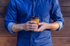 Equipaggi in camicia dei jeans che tiene la tazza di caffè fresco contro il fondo marrone potato vicino sulla foto di virile masc fotografie stock libere da diritti Equipaggi in camicia dei jeans che tiene la tazza di caffè fresco contro il fondo marrone potato vicino sulla foto di virile masc fotografie stock libere da diritti