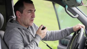 Equipaggi il microphon della mano del takinng e la conversazione sulla radio in sua automobile stock footage Equipaggi il microphon della mano del takinng e la conversazione sulla radio in sua automobile stock footage