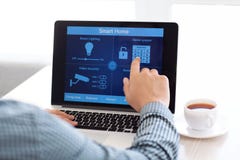 Equipaggi la seduta ad un computer portatile con la casa astuta di programma immagine stock libera da diritti Equipaggi la seduta ad un computer portatile con la casa astuta di programma immagine stock libera da diritti
