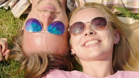 Equipaggi tenero baciare la donna sulla guancia, trovandosi sull'erba insieme, guardando il cielo blu stock footage Equipaggi tenero baciare la donna sulla guancia, trovandosi sull'erba insieme, guardando il cielo blu stock footage