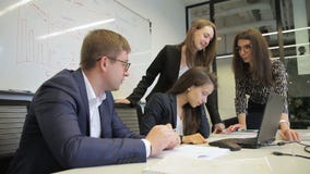 Equipe dos empregados que falam na mesa com o portátil na empresa vídeos de arquivo Equipe dos empregados que falam na mesa com o portátil na empresa vídeos de arquivo