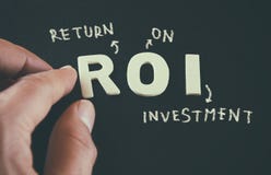 Equipe a mão que aponta nas palavras ROI Return On Investment escrito no fundo de couro preto fotografia de stock Equipe a mão que aponta nas palavras ROI Return On Investment escrito no fundo de couro preto fotografia de stock