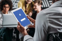equipe usando a tabuleta com facebook app na tela com seus sócios comerciais imagem de stock equipe usando a tabuleta com facebook app na tela com seus sócios comerciais imagem de stock