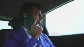 Equitação muçulmana nova do homem em um carro no banco traseiro e fala em um smartphone filme Equitação muçulmana nova do homem em um carro no banco traseiro e fala em um smartphone filme