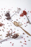 Erbsen des schwarzen, roten, weißen Pfeffers in den Metalllöffeln auf einem weißen Hintergrund Paprika, Paprika stockfotografie Erbsen des schwarzen, roten, weißen Pfeffers in den Metalllöffeln auf einem weißen Hintergrund Paprika, Paprika stockfotografie