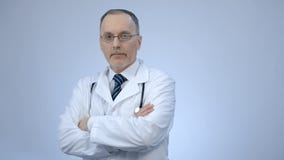Erfolgreicher überzeugter Doktor, der Kamera mit den gefalteten Armen, Klinikdienstleistungen betrachtet stockbild Erfolgreicher überzeugter Doktor, der Kamera mit den gefalteten Armen, Klinikdienstleistungen betrachtet stockbild