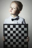 Ernstig Weinig jongen met schaakbord Fashion Children Vlinderdas Weinig geniekind stock afbeelding Ernstig Weinig jongen met schaakbord Fashion Children Vlinderdas Weinig geniekind stock afbeelding