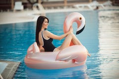 Erstaunliche sexy Frau trägt den schwarzen Bikini, der im Swimmingpool mit blauem Wasser auf einer rosa Flamingomatratze, Sommer lizenzfreies stockfoto Erstaunliche sexy Frau trägt den schwarzen Bikini, der im Swimmingpool mit blauem Wasser auf einer rosa Flamingomatratze, Sommer lizenzfreies stockfoto