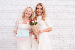 Erwachsene Mutter und Tochter werfen auf der Kamera zusammen nahe einer hellen Wand auf stockbild Erwachsene Mutter und Tochter werfen auf der Kamera zusammen nahe einer hellen Wand auf stockbild